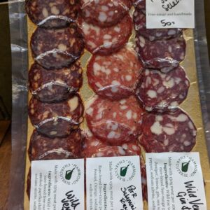 A vac pack of sliced salami filling a gold board, three colours of salami and labels showing each variety